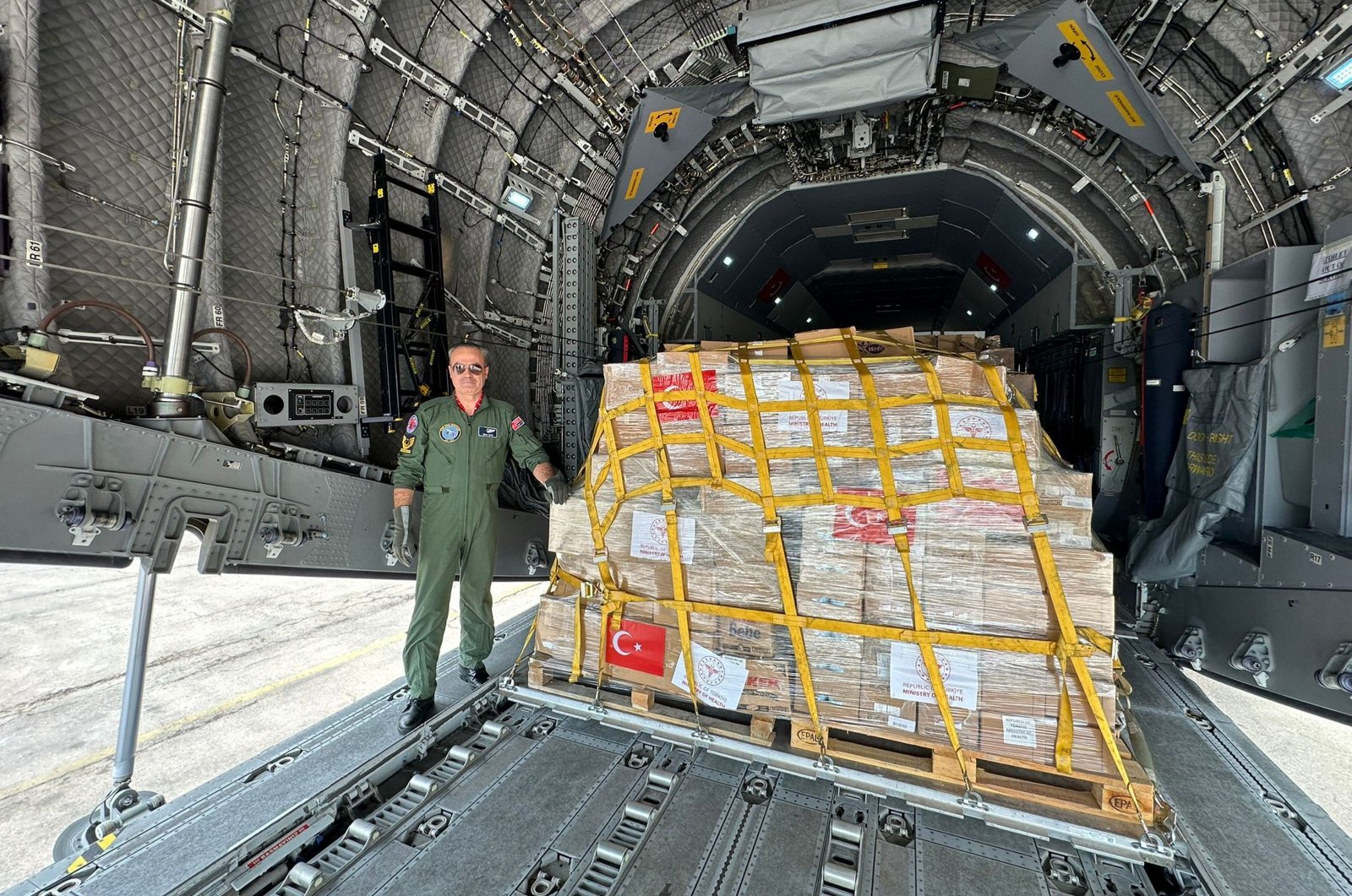 A Defense Ministry official poses next to crates of medical supplies on the ramp of a military transport plane headed for Gaza, Amman, Jordan, March 5, 2024. (AA Photo)