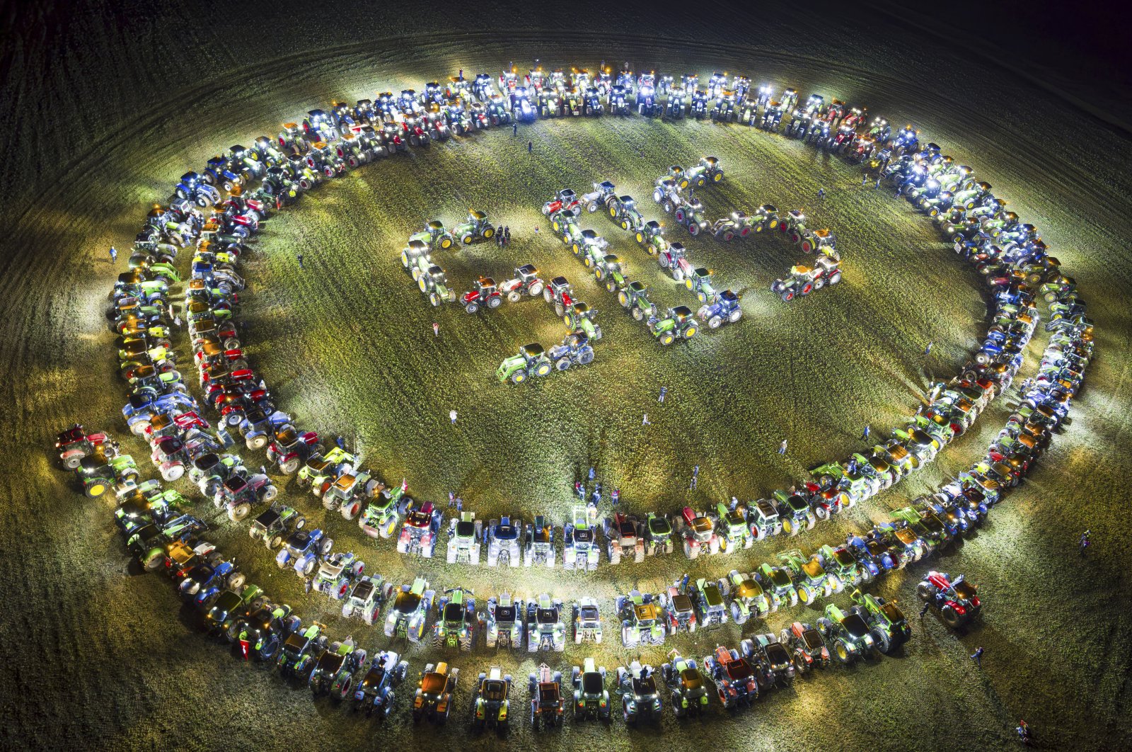 Farmers organize themselves to form a giant &quot;SOS&quot; signal with their tractors as coordinated stunt replicated in various locations across Switzerland, protesting against their work conditions and here specifically the price of milk, echoing numerous protests across Europe in the recents weeks, in a field between the villages of Echallens and Goumoens-la-Ville, Switzerland, Feb. 29, 2024. (AP Photo)