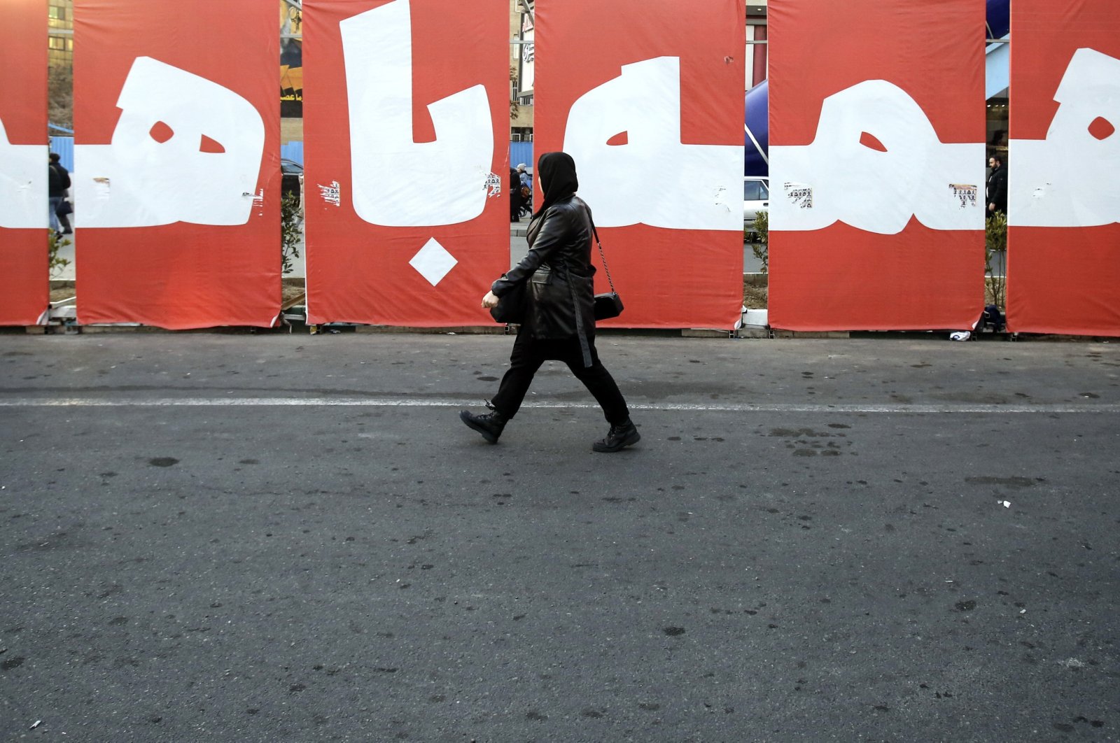 An Iranian woman walks past a huge banner reading in Persian &#039;All together for homeland&#039; in a street in Tehran, Iran, March 4, 2024. (EPA Photo)