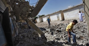 Syrians check the damage at a destroyed school after it was hit by an airstrike killing six Syrians in the town of Tal Rifaat on the outskirts of Aleppo, Syria, Aug. 8, 2012. (AP File Photo)
