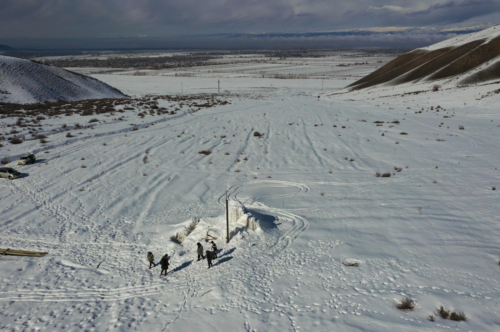 A group of men, including farmer Erkinbek Kaldanov, 54, and Syn-Tash district chief Maksat Dzholdoshev, is seen near the artificial glacier in a mountain gorge near the village of Syn-Tash, some 60 kilometers (37 miles) from Bishkek, Kyrgyzstan, Feb. 13, 2024. (AFP Photo)