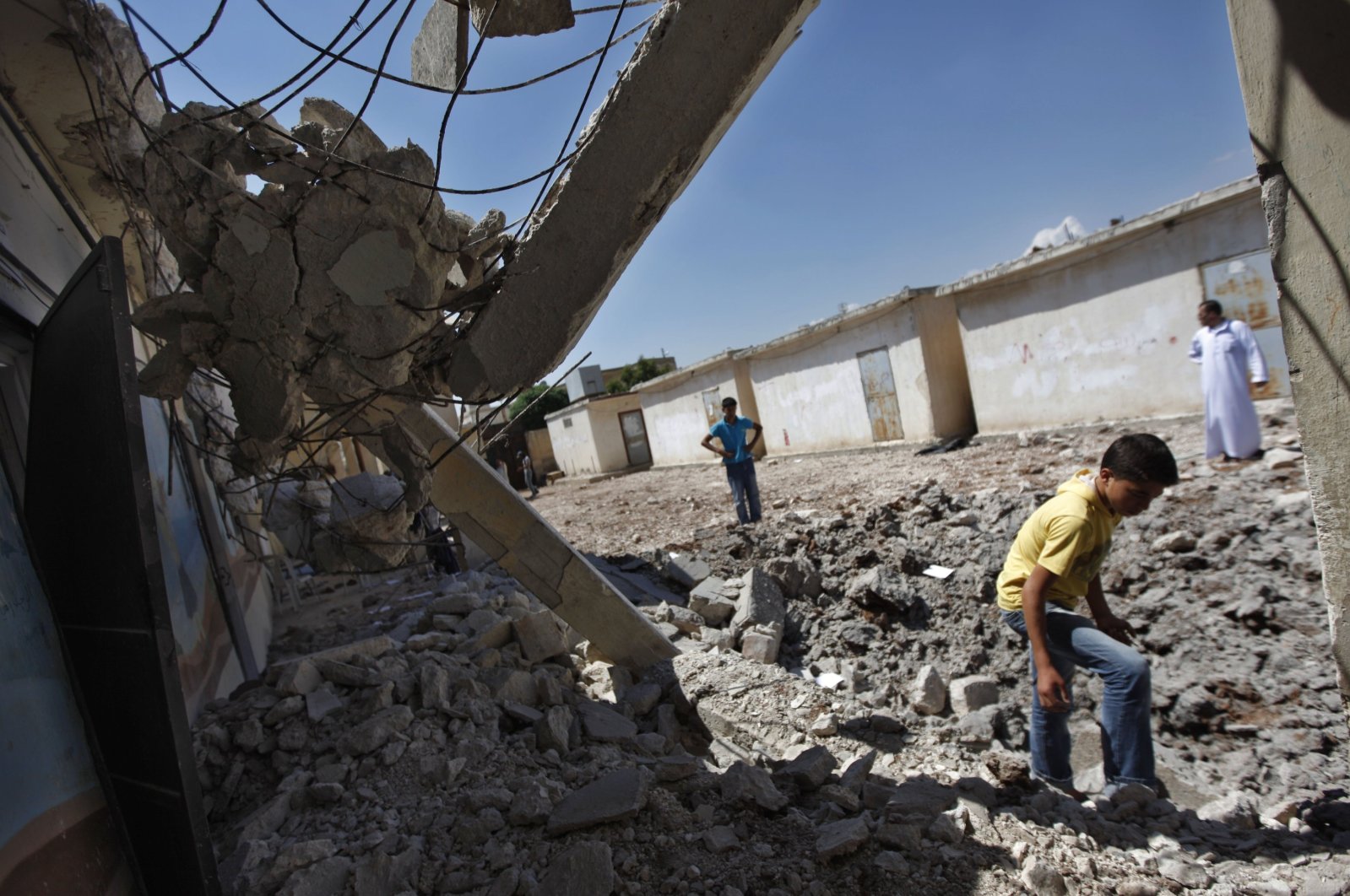 Syrians check the damage at a destroyed school after it was hit by an airstrike killing six Syrians in the town of Tal Rifaat on the outskirts of Aleppo, Syria, Aug. 8, 2012. (AP File Photo)