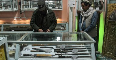 A Taliban security personnel (L) and a visitor look at the antiques in a museum inside the Shrine of Hazrat Ali or Blue Mosque, in Mazar-i-Sharif, Afghanistan, March 4, 2024. (AFP Photo)