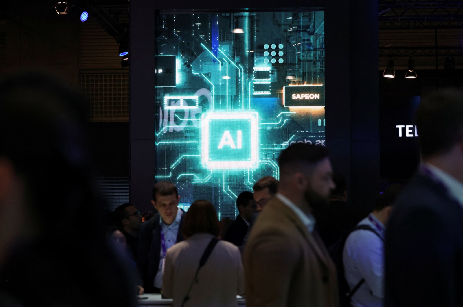 People walk near a sign for Sapeon, an artificial intelligence (AI) chip company, at the Mobile World Congress (MWC) in Barcelona, Spain, Feb. 27, 2024. (Reuters Photo)