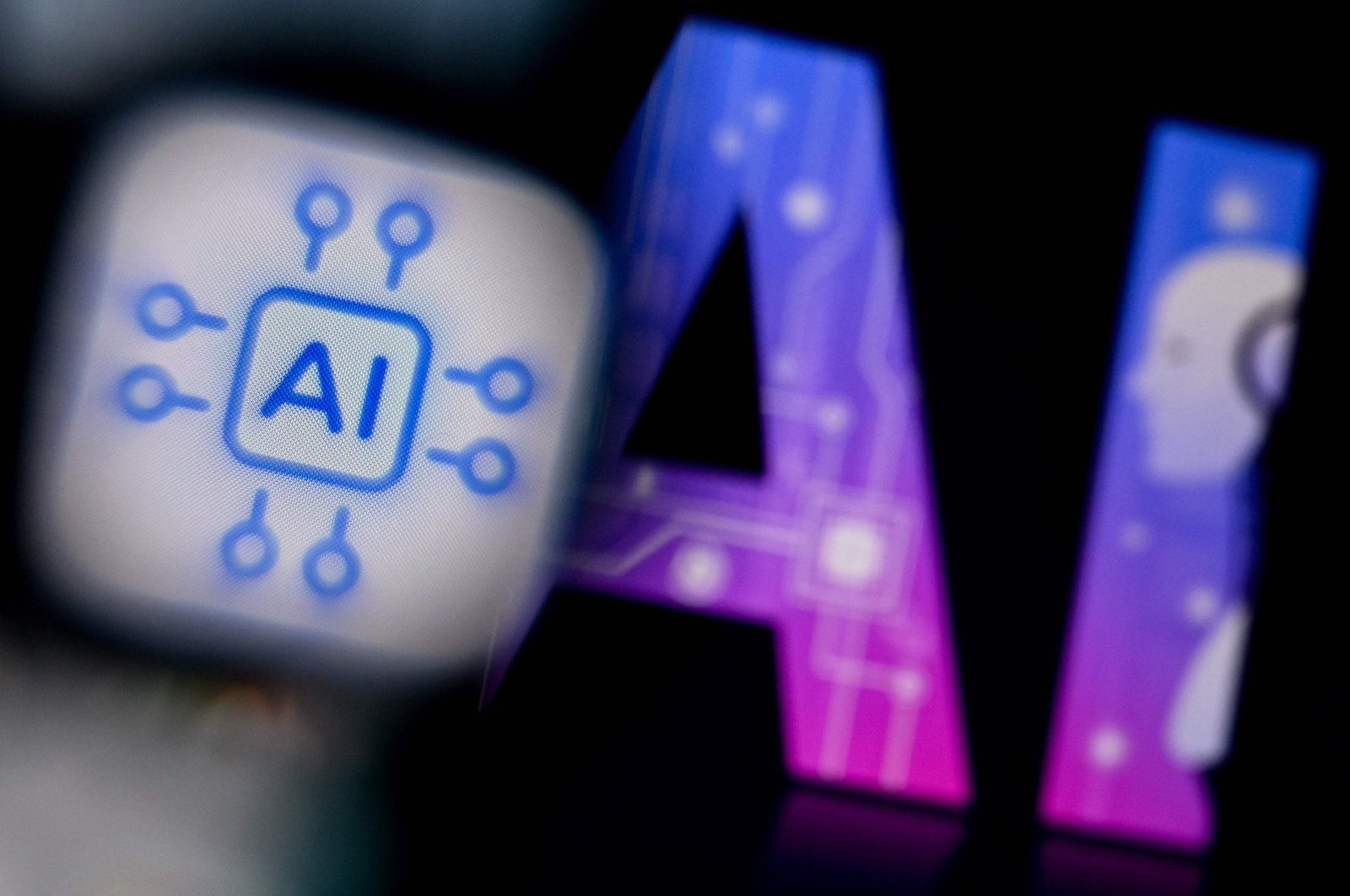 An artificial Intelligence logo is displayed on a smartphone screen (L) and the letters AI on a laptop screen in Frankfurt am Main, western Germany, Feb. 26, 2024. (AFP Photo)