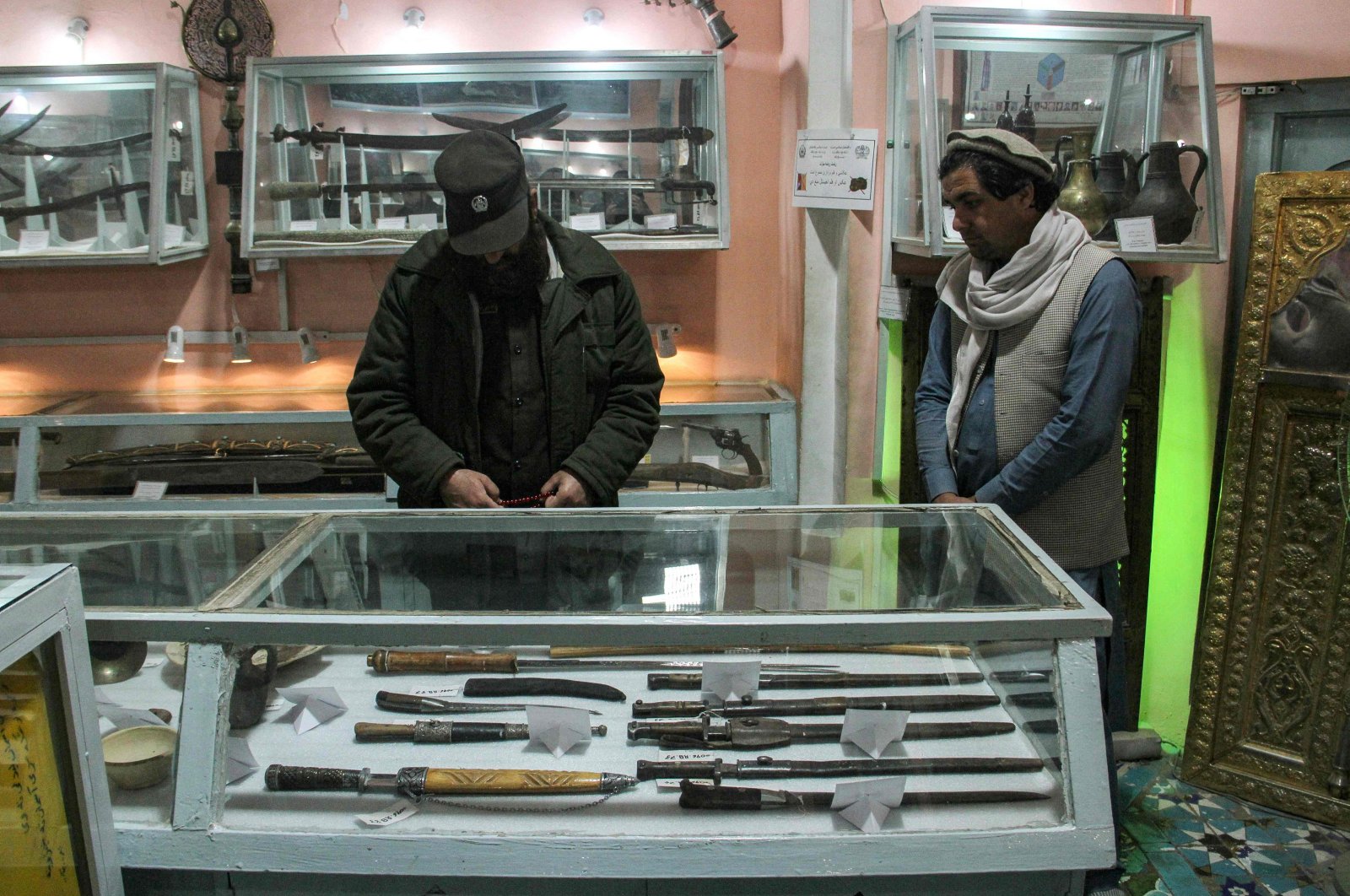 A Taliban security personnel (L) and a visitor look at the antiques in a museum inside the Shrine of Hazrat Ali or Blue Mosque, in Mazar-i-Sharif, Afghanistan, March 4, 2024. (AFP Photo)