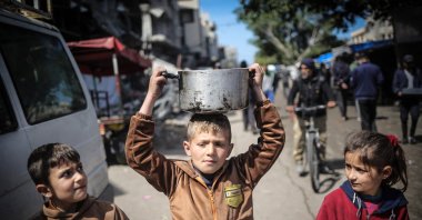 Palestinian children carry kitchen utensils as they walk toward a food distribution point in Khan Yunis, Gaza Strip, Palestine, March 7, 2024. (AFP Photo)