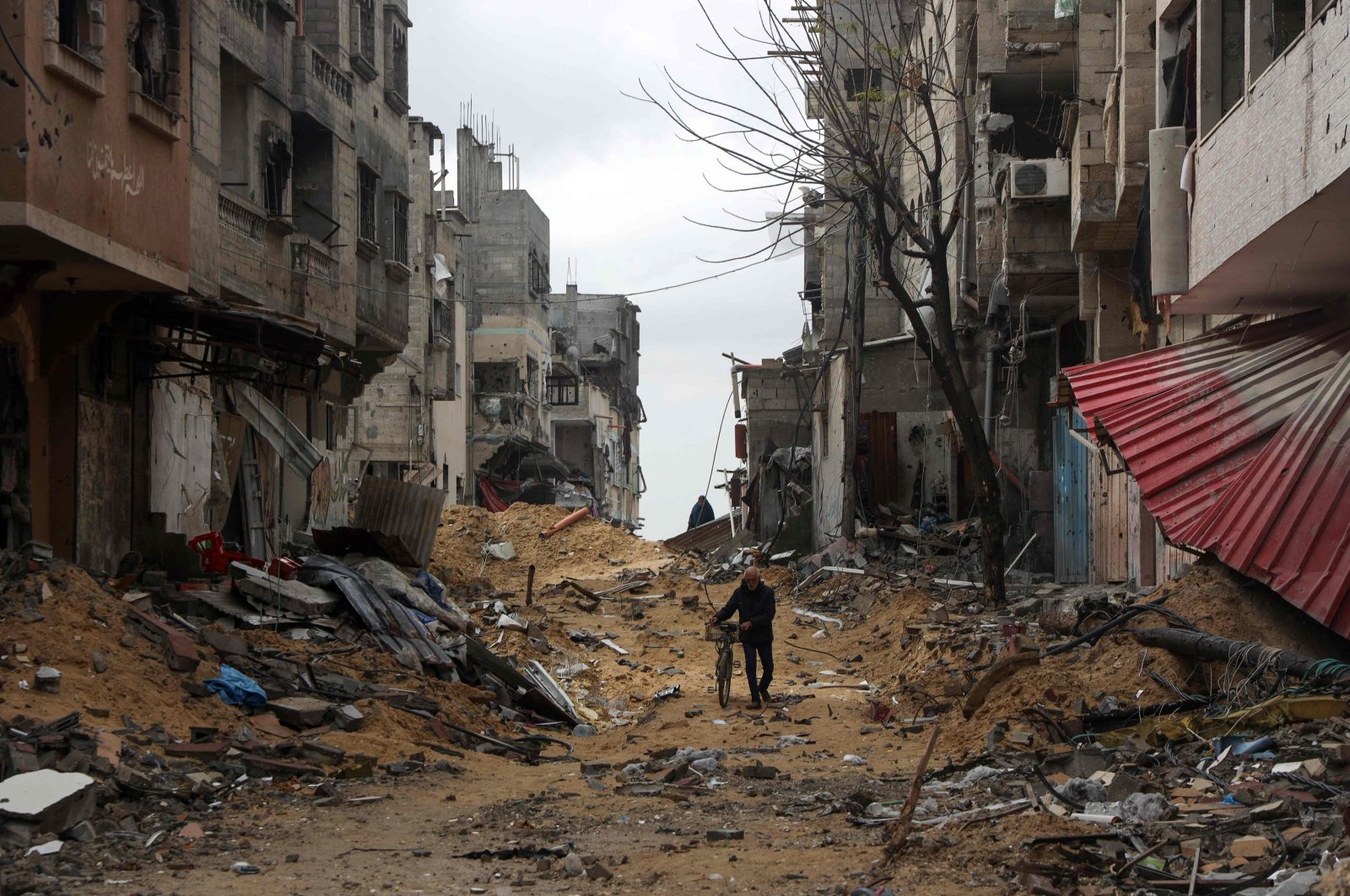 A Palestinian man pushes his bicycle as he walks amid buildings destroyed in Israeli bombing as they flee Khan Yunis in the southern Gaza Strip, Palestine, March 7, 2024. (AFP Photo)