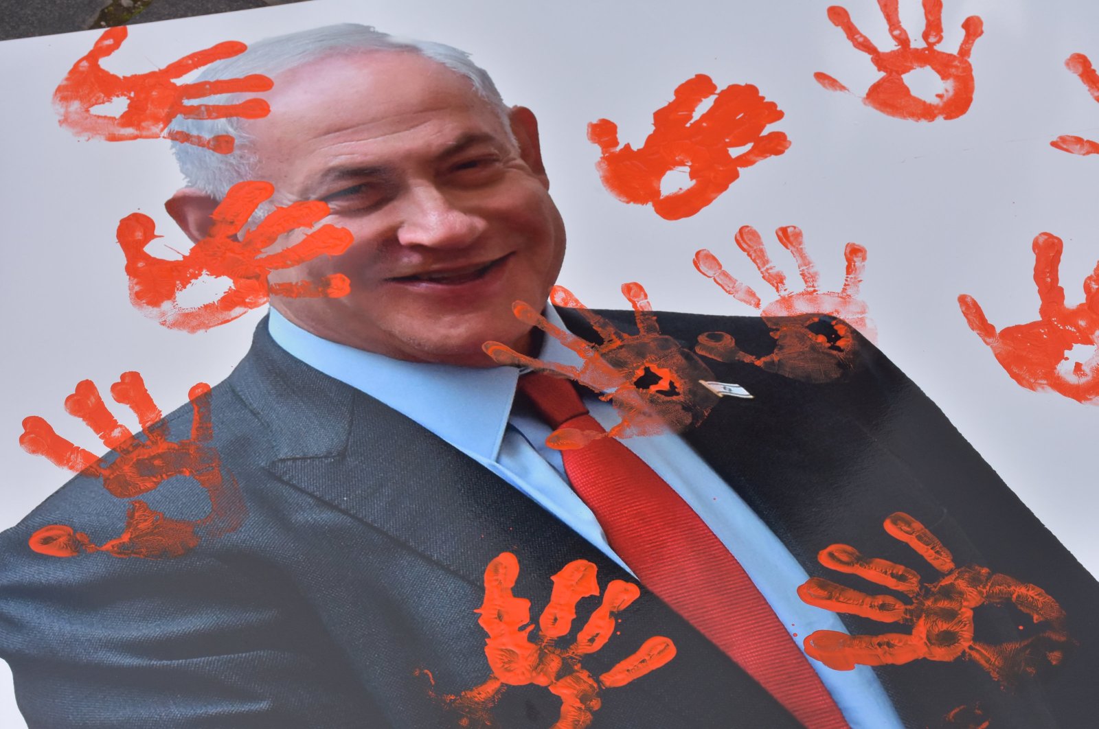 A poster of Israeli Premier Benjamin Netanyahu lies covered in red handprints during a pro-Palestine protest in Rome, Italy, March 2, 2024. (AA Photo)