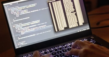 The source code of a web server and the Windows prompt can be seen on a laptop in the dark, Feb. 11, 2024. (Reuters File Photo)