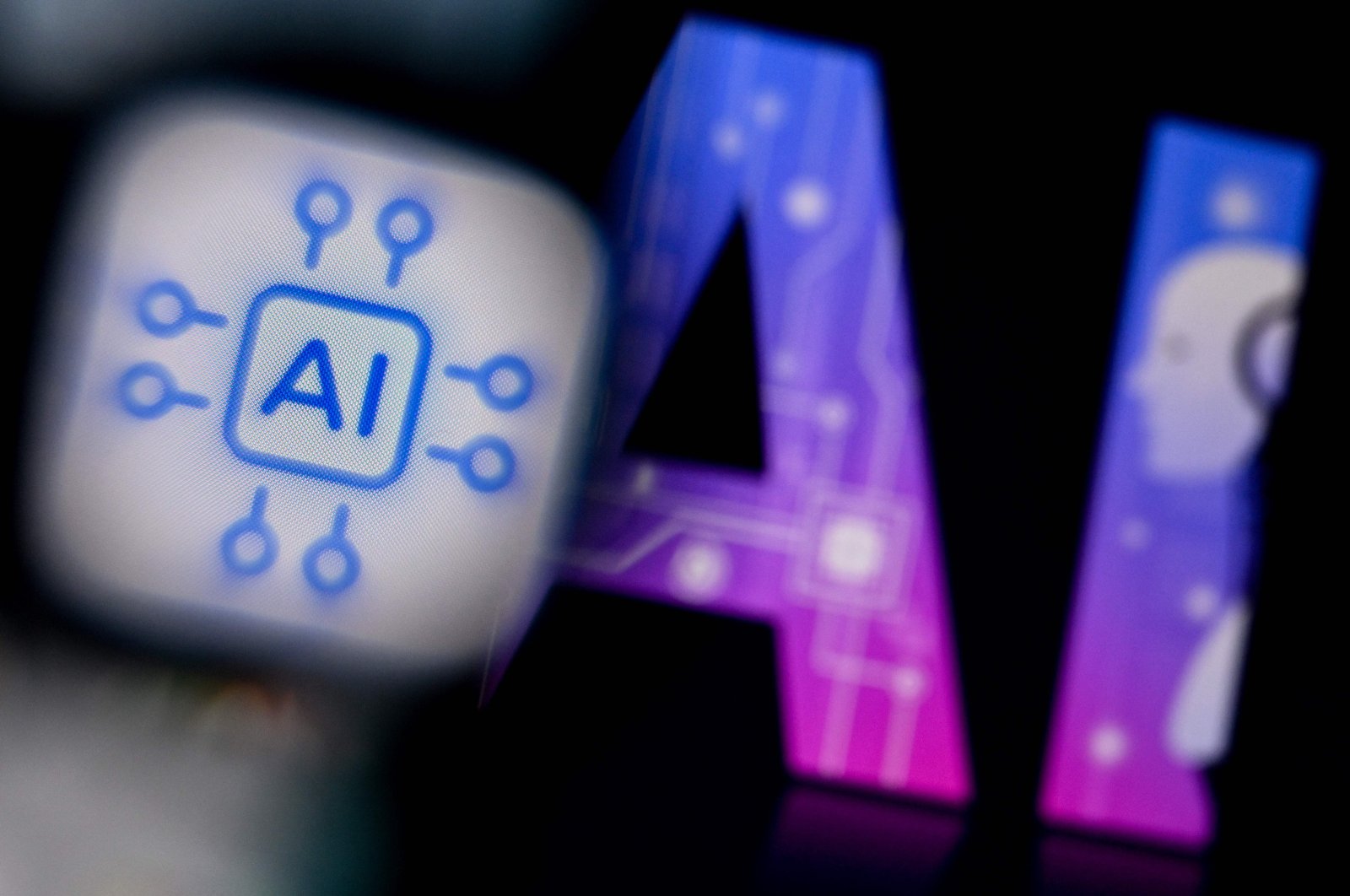 A photo shows the logo of the Artificial Intelligence chat application on a smartphone screen (L) and the letters AI on a laptop screen in Frankfurt, Germany, Feb. 26, 2024. (AFP Photo)