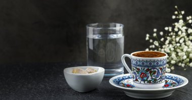 A traditional cup of Turkish coffee with foam, water glass and Turkish delights. (Shutterstock Photo)