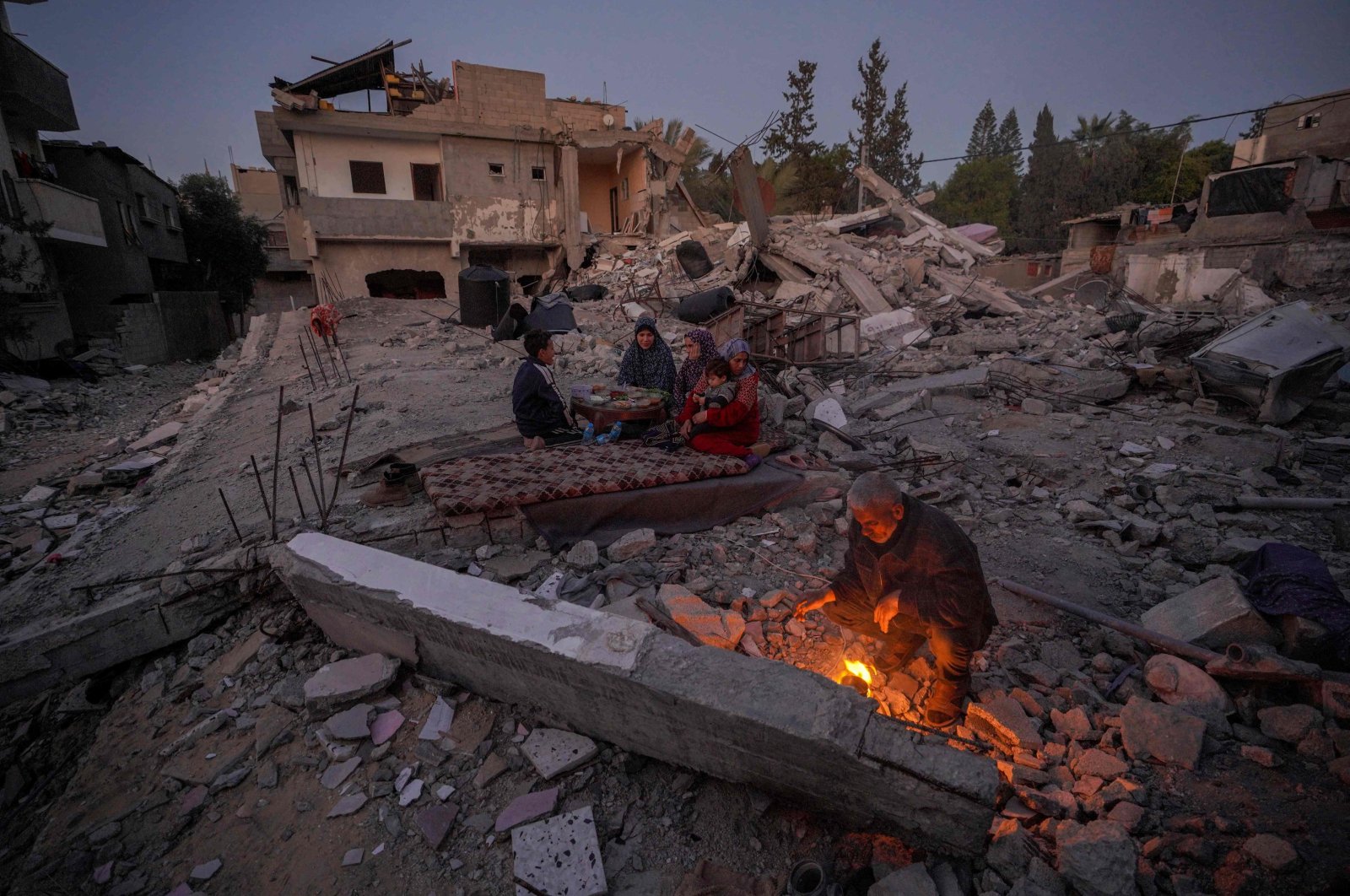 The Palestinian al-Naji family prepares to break their fast during the first day of the Islamic holy fasting month of Ramadan sitting amidst the ruins of their family house in Deir al-Balah, central Gaza Strip, Palestine, March 11, 2024. (AFP Photo)