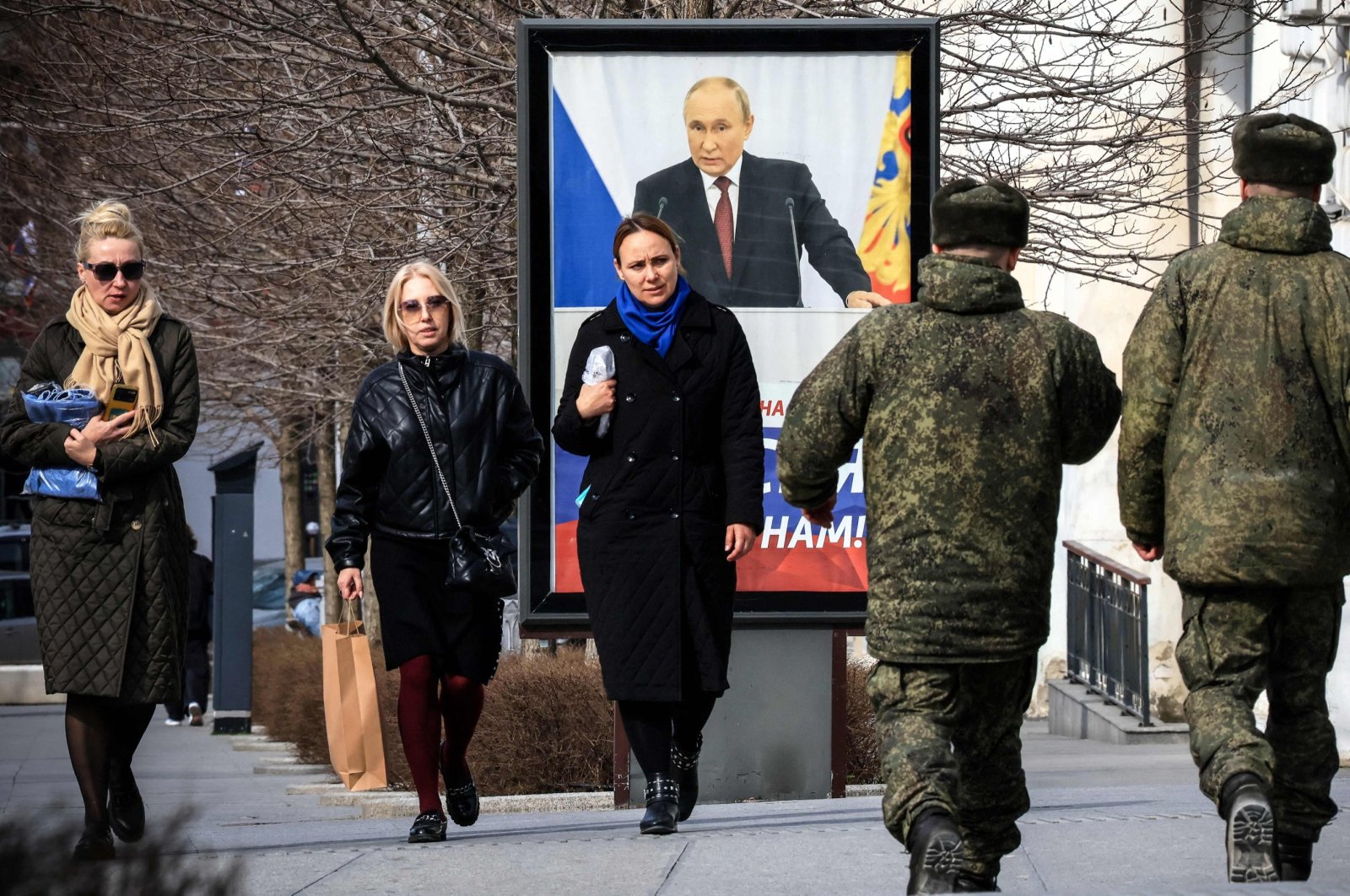 People walk in front of a poster showing Russian President Vladimir Putin and reading "The West doesn&#039;t need Russia. We need Russia!" Simferopol, occupied Crimea, Feb. 29, 2024. (AFP Photo)