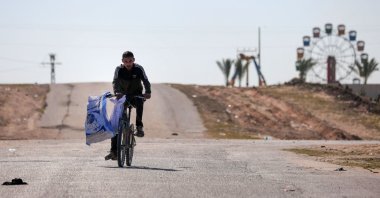 A displaced Palestinian man flees on his bicycle the Hamad City area in Khan Younis in the southern Gaza Strip, Palestine, March 5, 2024. (AFP Photo)