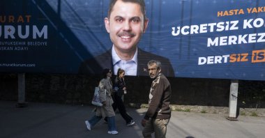 People walk in front of a local election campaign poster of Istanbul mayoral candidate Murat Kurum of the ruling AK Party (Justice and Development Party), on a street in Istanbul, Türkiye, Feb. 27, 2024. (EPA Photo)