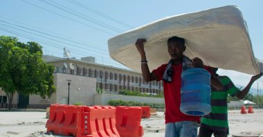 Two people carry a mattress as they walk past the U.S. embassy in Port-au-Prince, Haiti, March 12, 2024. (AFP Photo)