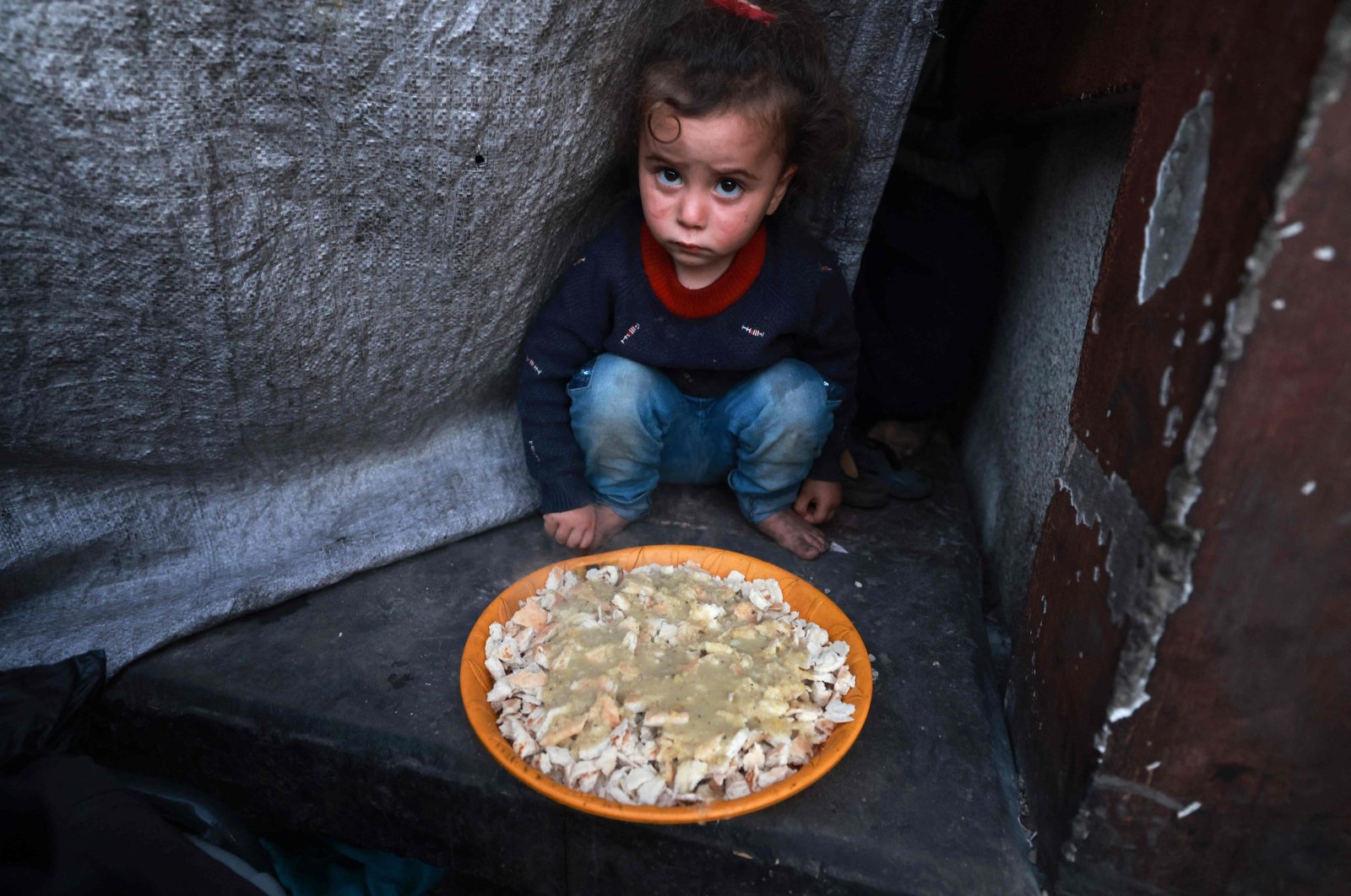 A Palestinian child sits next to a plate before an iftar meal, the breaking of the fast meal, on the second day of the holy fasting month of Ramadan, at a shelter for displaced people in Rafah, in the southern Gaza Strip, Palestine, March 12, 2024. (AFP Photo)