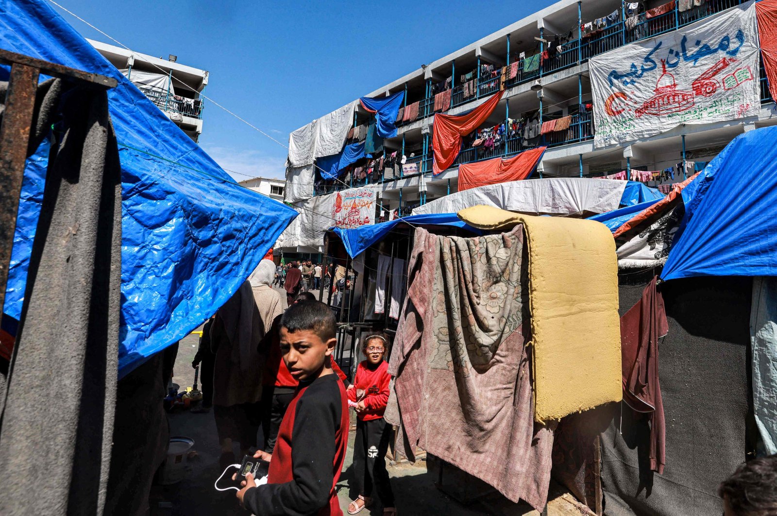 Sheets showing greeting messages for the Islamic holy month of Ramadan hang outside buildings at a refugee camp in Rafah, southern Gaza Strip, Palestine, March 13, 2024. (AFP Photo)