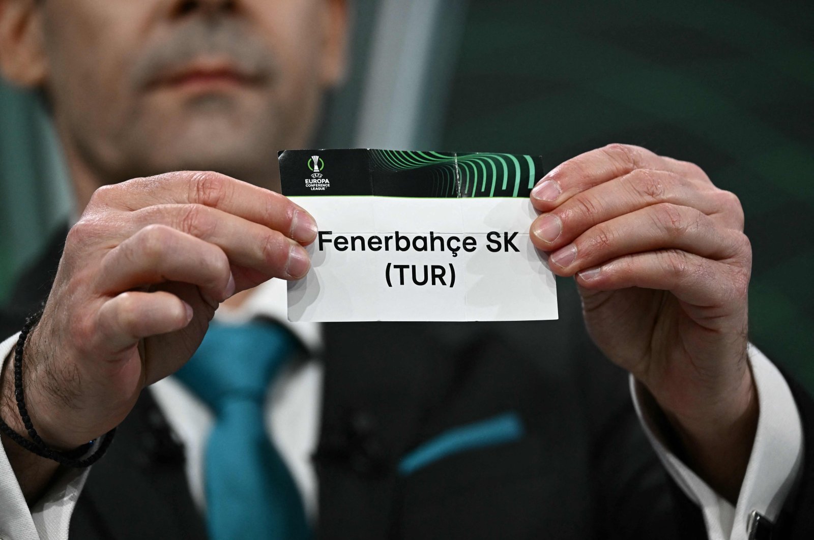 Greek former footballer Vasilios Tsiartas holds the paper slip of Fenerbahce during the 2023-2024 UEFA Europa Conference League football tournament quarterfinals and semifinals draw at the House of European Football, Nyon, Switzerland, March 15, 2024. (AFP Photo)