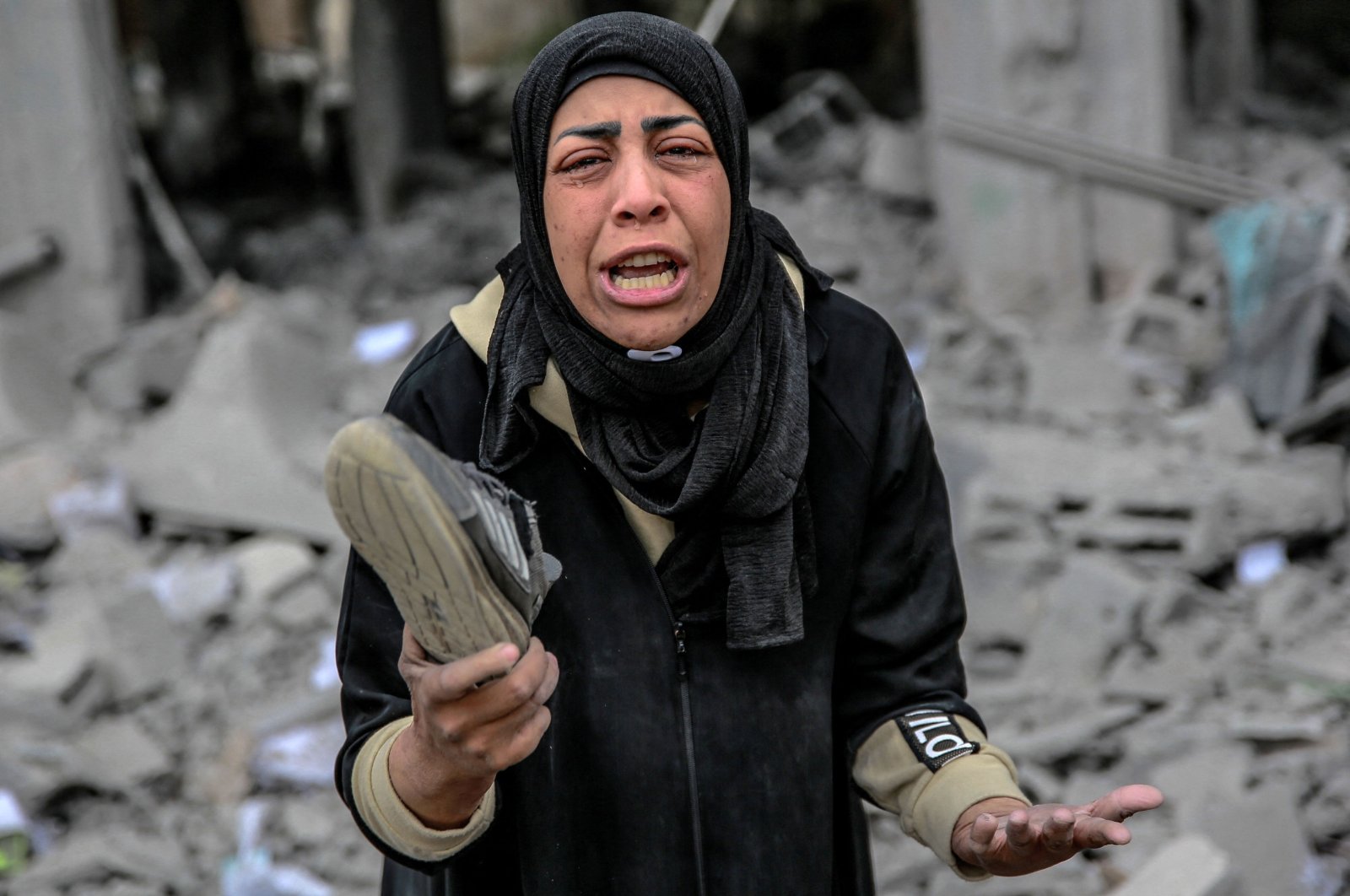 A Palestinian woman reacts as she holds a shoe that belonged to a loved one killed in Israeli attacks in the Rimal neighborhood of Gaza City, Palestine, March 16, 2024. (AFP Photo)