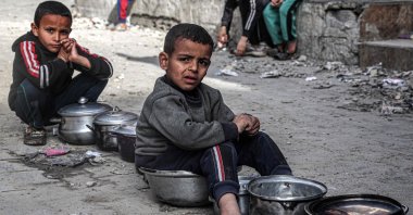 Boys sit with empty pots as displaced Palestinians wait for meals provided by a charity organization ahead of the fast-breaking "iftar" meal during Islam's holy month of Ramadan, in Rafah, southern Gaza Strip, Palestine, March 16, 2024. (AFP Photo)