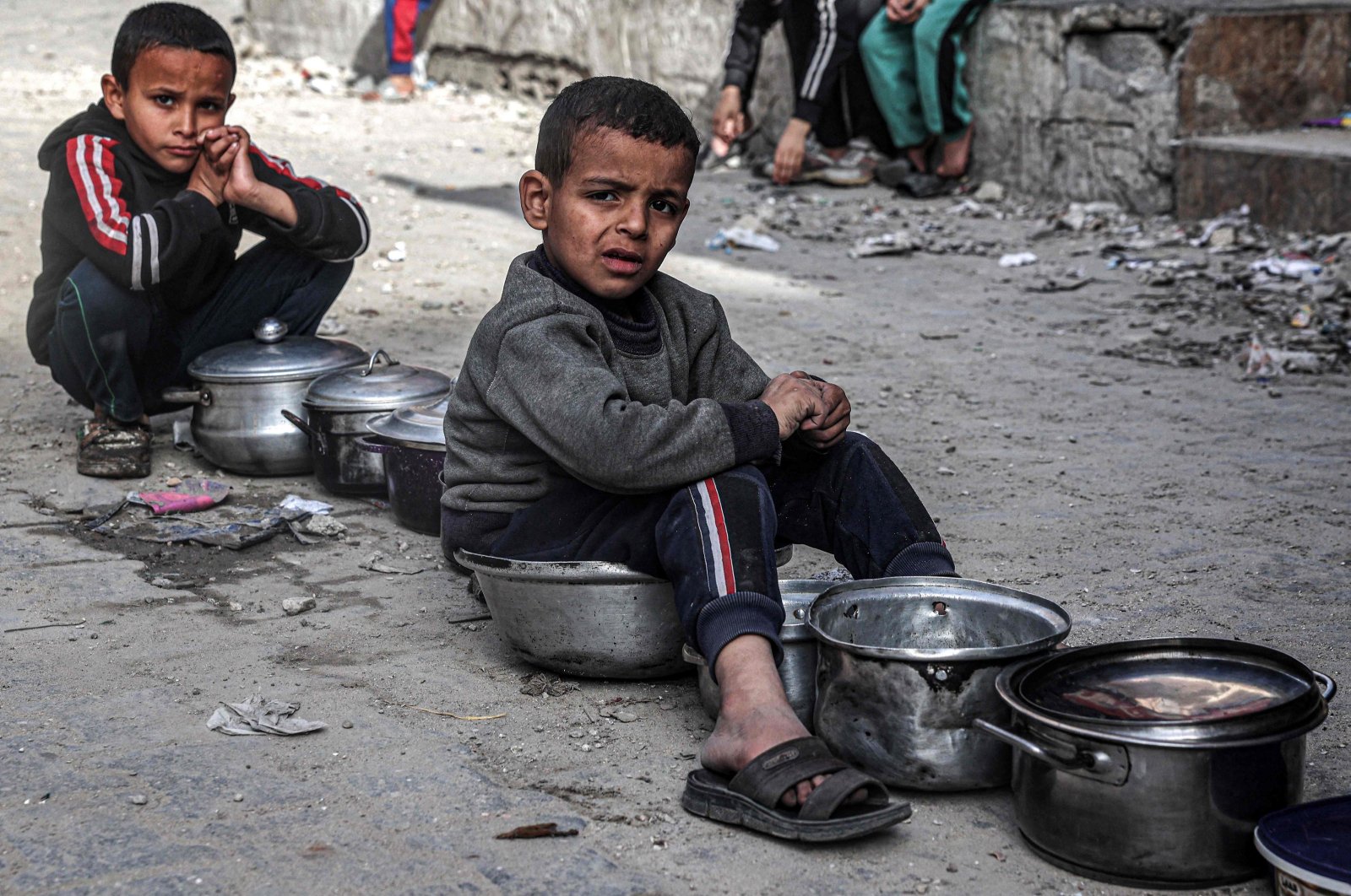 Boys sit with empty pots as displaced Palestinians wait for meals provided by a charity organization ahead of the fast-breaking &quot;iftar&quot; meal during Islam&#039;s holy month of Ramadan, in Rafah, southern Gaza Strip, Palestine, March 16, 2024. (AFP Photo)