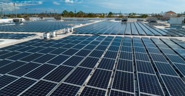 Aerial view of solar panels mounted on an industrial building roof used in producing clean electricity. (Shutterstock Photo)