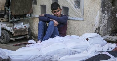 A Palestinian youth sits next to bodies of loved ones killed in Israeli airstrikes, Deir al-Balah, Gaza Strip, March 20, 2024. (EPA Photo)