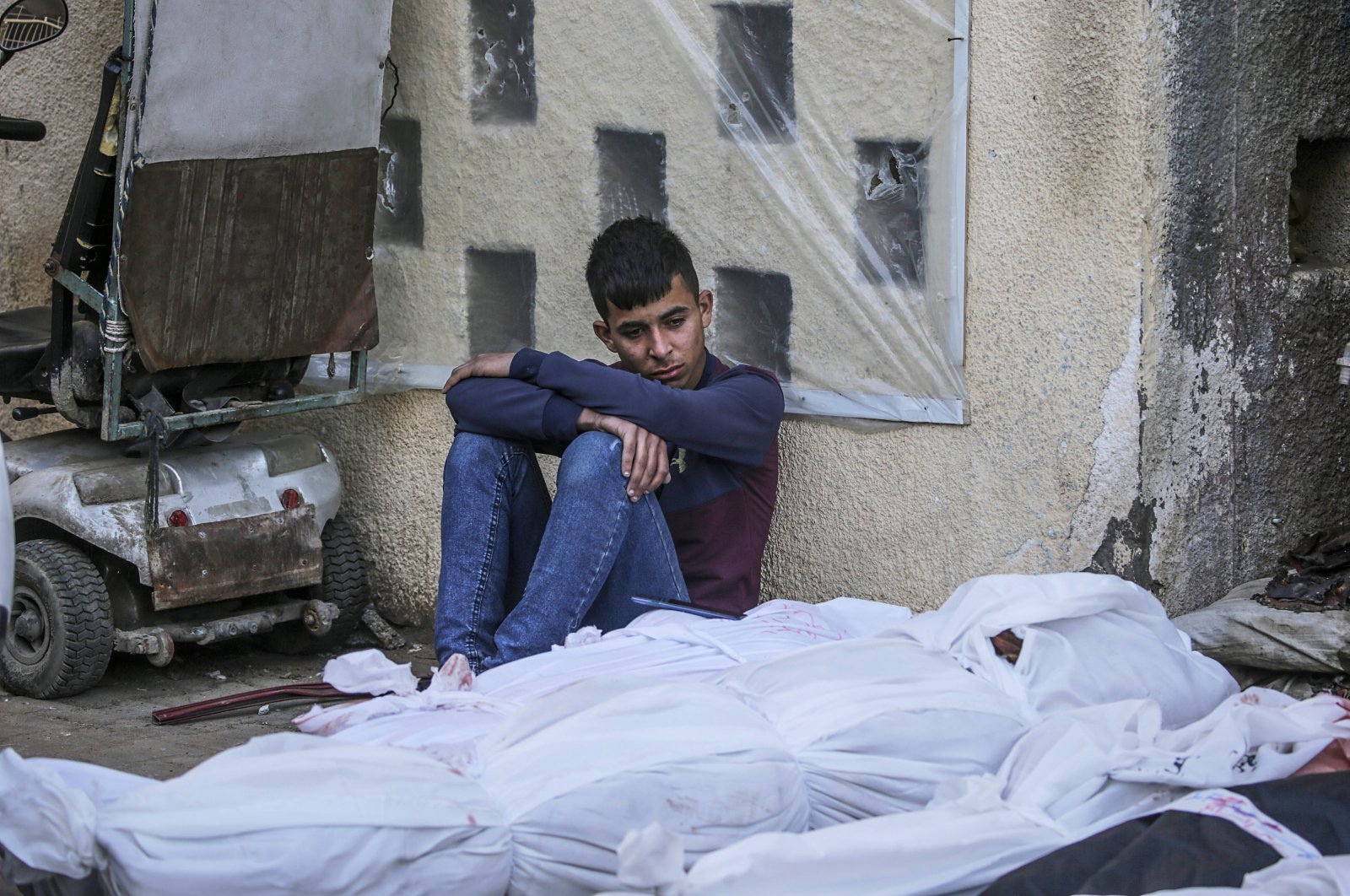 A Palestinian youth sits next to bodies of loved ones killed in Israeli airstrikes, Deir al-Balah, Gaza Strip, March 20, 2024. (EPA Photo)
