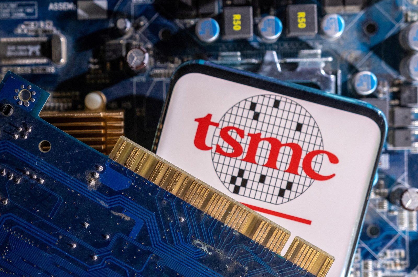 A smartphone with a displayed Taiwan Semiconductor Manufacturing Company (TSMC) logo is placed on a computer motherboard in this illustration taken on March 6, 2023. (Reuters Photo)