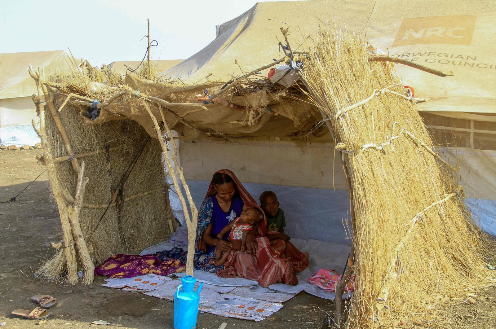 An internally displaced woman and her children sit in the shade of a straw hut at a camp in southern Gadaref state, Sudan, March 20, 2024. (AFP Photo)
