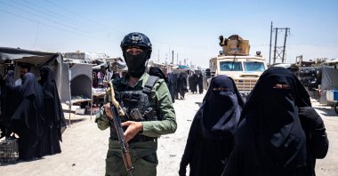 Women walk past a YPG/PKK terrorist at the YPG/PKK-run al-Hol camp holding families of Daesh terrorists, northeastern al-Hassakeh Governorate, Syria, Oct. 10, 2023. (AFP Photo)