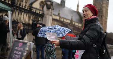 A food poverty campaigner with Mother's Manifesto hands out fliers as they demonstrate outside Parliament on Mother's Day, London, Britain, March 10, 2024. (EPA Photo)