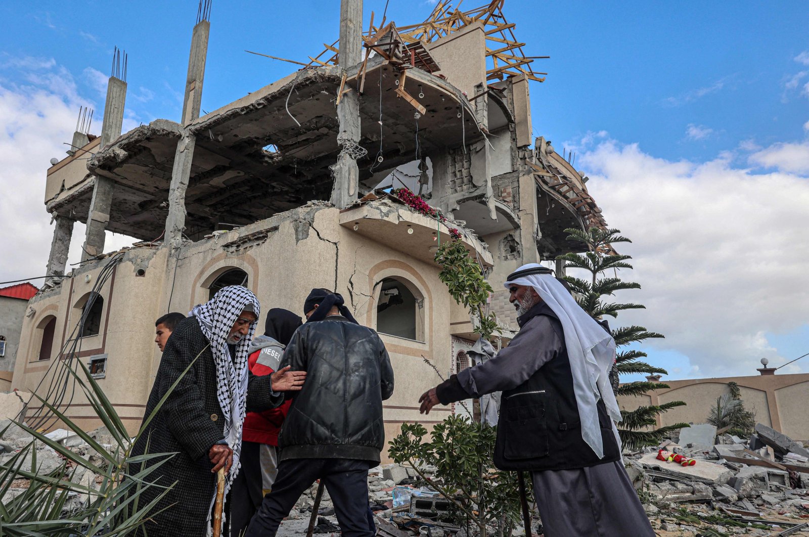 Palestinian men and boys walk in front of a house damaged by Israeli bombardment in Rafah, the southern Gaza Strip, Palestine, March 22, 2024. (AFP Photo)
