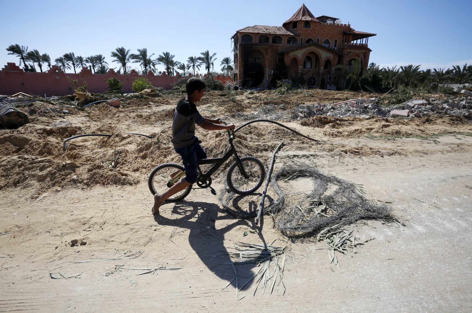 A Palestinian boy rides a bike in front of a building damaged in Israeli attack on Deir al-Balah, Gaza, Palestine, March 23, 2024. (AA Photo)