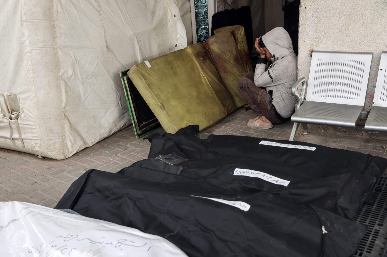 A young Palestinian boy reacts as he sits between a blood-stained mattress and body bags at the al-Najjar hospital, following overnight Israeli bombardment in Rafah, Gaza Strip, Palestine, March 24, 2024. (AFP Photo)