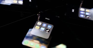 This photo shows reflections on a smartphone screen of logos of online platforms Google, Facebook, LinkedIn, Amazon, Apple store and TikTok, Brussels, Belgium, Feb. 12, 2023. (AFP Photo)