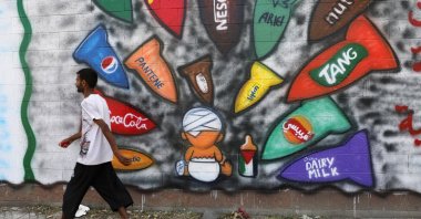 A man walks past graffiti calling for the boycott of several products, in solidarity with the Palestinians, Sanaa, Yemen, March 21, 2024. (Reuters Photo)