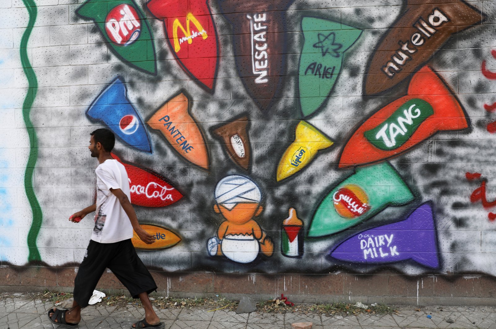 A man walks past graffiti calling for the boycott of several products, in solidarity with the Palestinians, Sanaa, Yemen, March 21, 2024. (Reuters Photo)