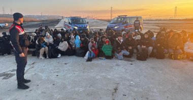 A gendarmerie officer stands guard over a group of irregular migrants caught with two smugglers, off the coast of western Çanakkale province, Türkiye, March 19, 2024. (DHA Photo)