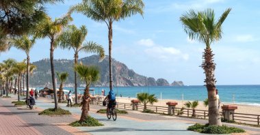 A person pedals close to the coast of a palm-dotted path, Alanya, southern Türkiye, April 8, 2021. (Shutterstock Photo)
