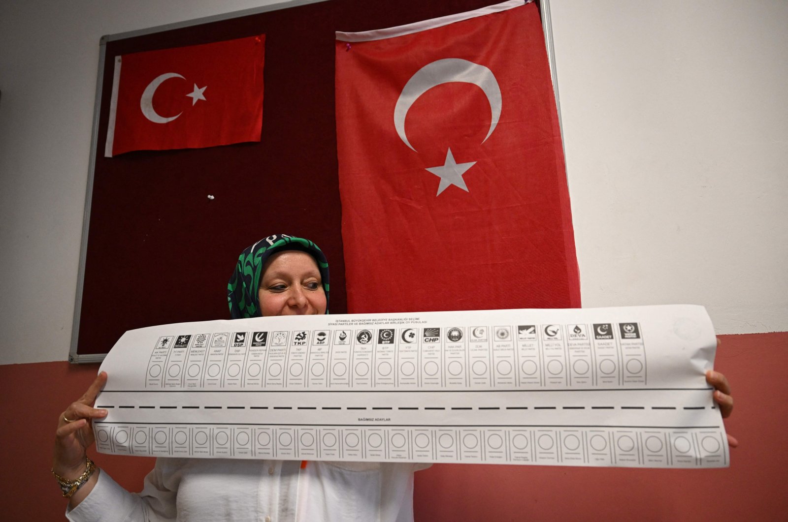 A poll worker holds a ballot reading "Istanbul mayoral election: combined ballots from political parties and independent candidates" at the start of the municipal elections, Istanbul, Türkiye, March 31, 2024. (AFP Photo)