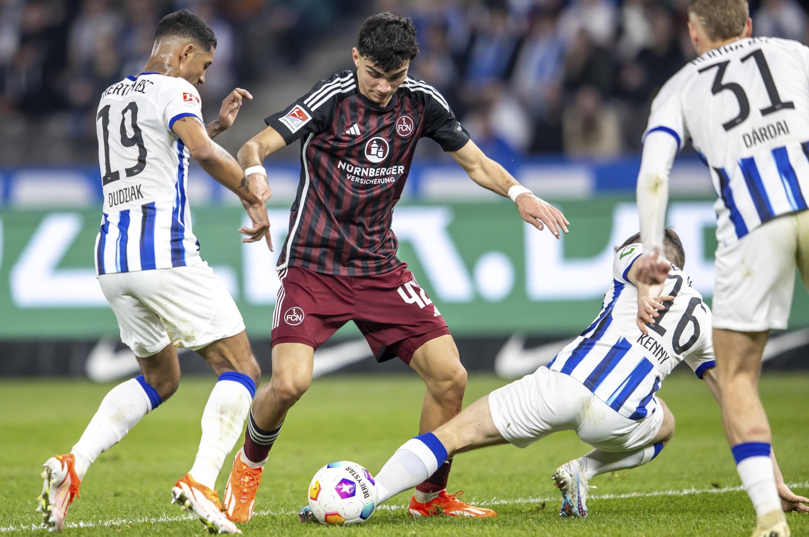 Nuremberg&#039;s Can Uzun (C) vies for the ball with Berlin&#039;s Jeremy Dudziak (L) and Jonjoe Kenny during the Bundesliga second division match, March 30, 2024. (AP Photo)