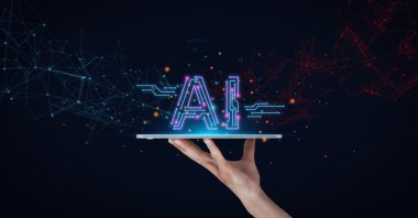 AI signage is written over a screen being held up by a hand. (Shutterstock Photo)