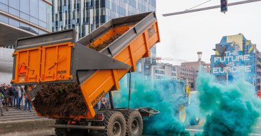 Farmers drop earth between flares lit by protesters on the side of an Agriculture and Fisheries Council in Brussels, Belgium, March 26, 2024. (EPA Photo)