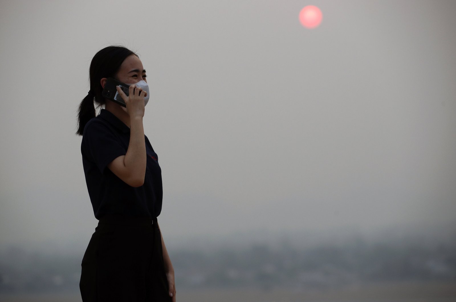 A Thai woman speaking on a mobile phone wears a mask amid smog from heavy concentrations of fine particulates matter PM2.5, in Chiang Mai province, northern Thailand, March 15, 2024. (EPA Photo)