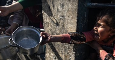 A displaced Palestinian child holds up an empty pot as she waits with others to receive food aid provided by a Palestinian youth group in the Rafah refugee camp, Gaza Strip, Palestine, Jan. 25, 2024. (EPA Photo)