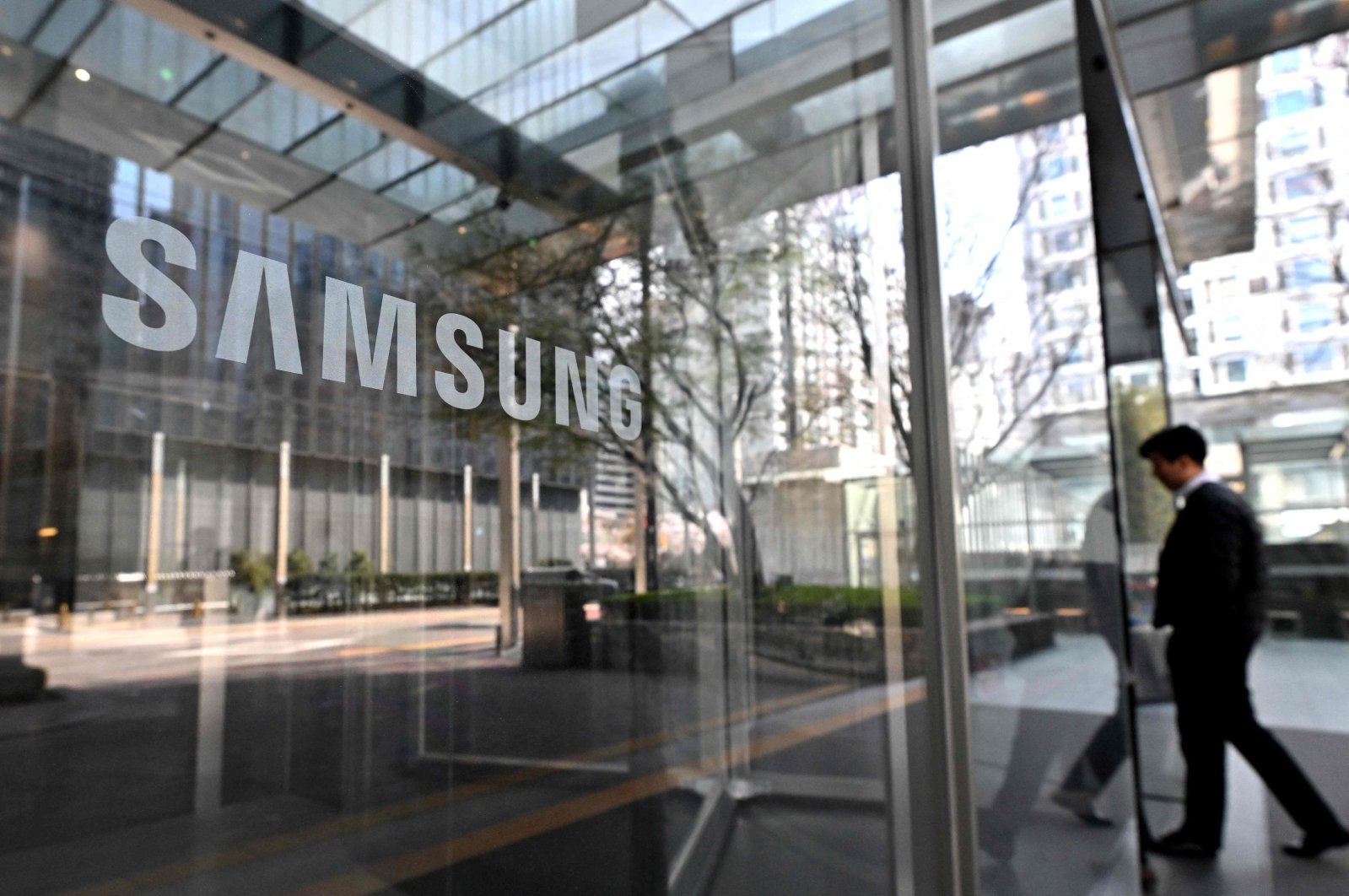 A man walks past the Samsung logo displayed on a glass door at the company&#039;s Seocho building in Seoul, South Korea, April 5, 2024. (AFP Photo)