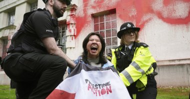 Police officers detain a person after members of Youth Demand threw red paint over the exterior of the Ministry of Defense building, London, U.K., April 10, 2024. (AP Photo)